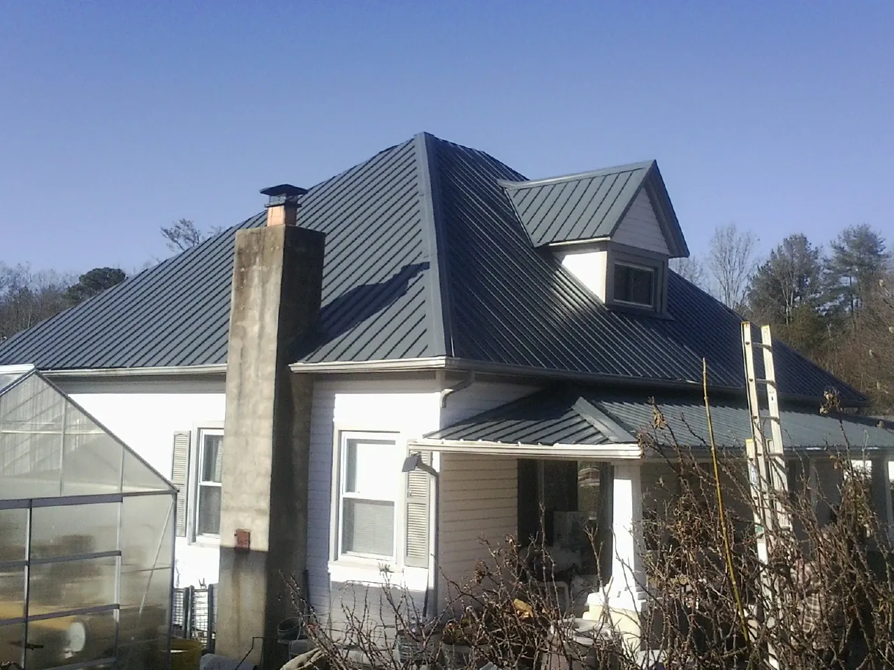 Dark blue standing seam metal roof on a white farmhouse with dormer — Slate & Tile Roof Repair by Roofing Brothers in Scandia