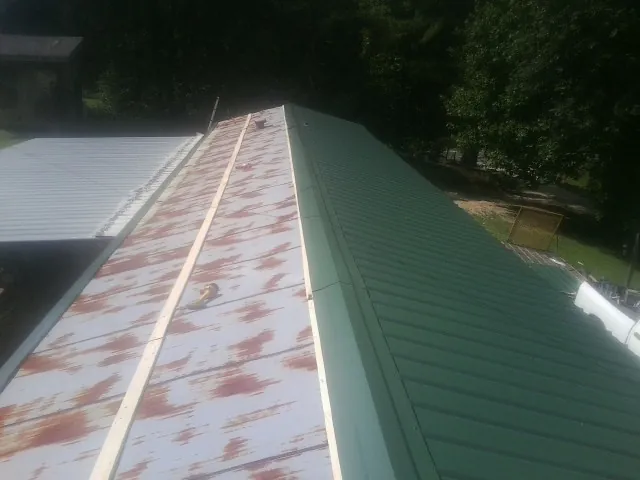 Old rusted panels beside newly installed green metal roofing — Wind Damage Roof Repair by Roofing Brothers in Scandia