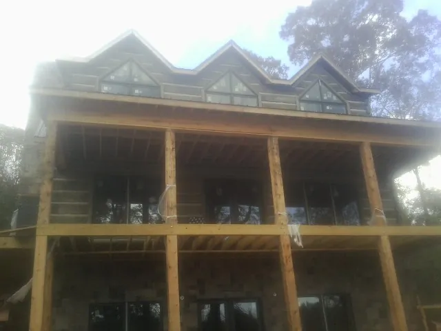 Dormers and porch framing on a large log home under construction — Roof Coating work by our crew in Scandia