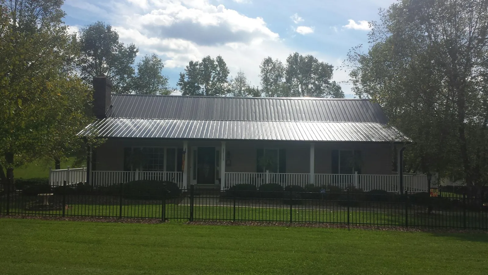 Gray metal roof on a brick ranch with a full width front porch — Gutter Guard Installation work by our crew in Scandia
