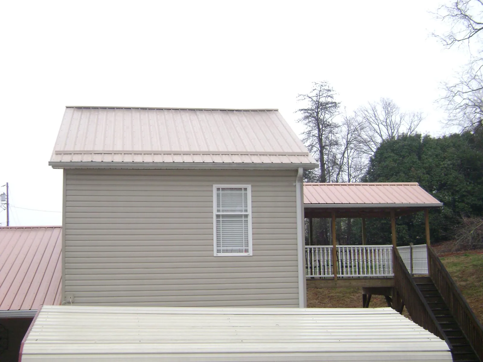 Tan metal roofs on a two story addition and attached porch, from a Roof Replacement job in Scandia