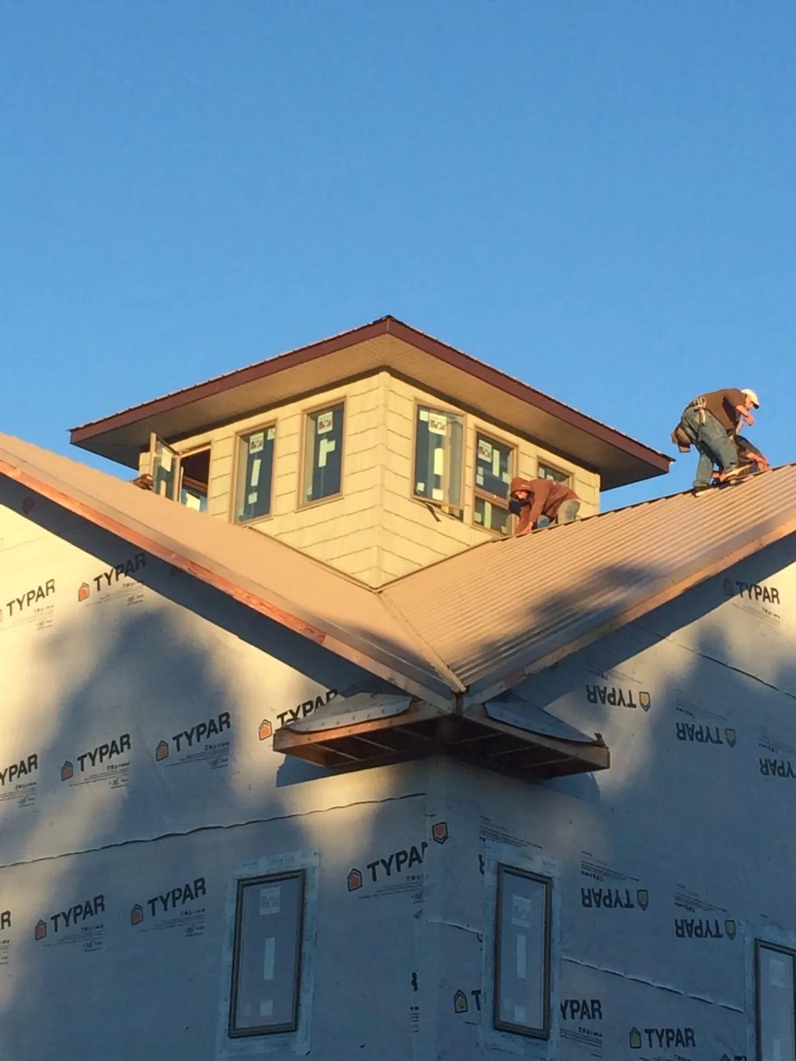 Roofers working around a rooftop cupola on a new metal roof at sunset — Roof Waterproofing in Scandia by Roofing Brothers